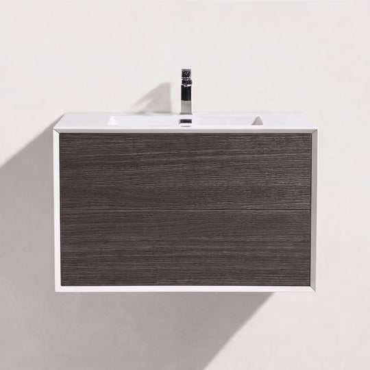 A modern wall-mounted bathroom vanity with two dark brown graphite wood drawers, a white top, and a black faucet, shown against a plain off-white wall.