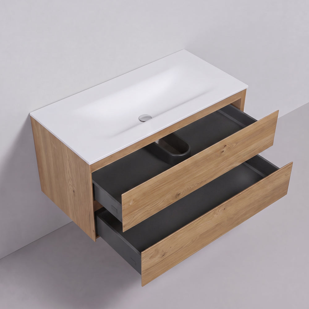 A modern wall-mounted bathroom vanity with a white integrated sink top, light oak wood grain cabinet, and two open dark gray drawers, shown against a light gray wall and floor.