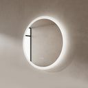 BAI 21011 modern minimalist round 30-inch bathroom vanity mirror with a glowing white LED light ring, mounted on a textured beige plaster wall.