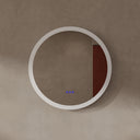 A minimalist round wall mirror with a thick frosted edge frame, mounted on a textured beige plaster wall. The right half of the mirror surface is covered by a solid dark reddish-brown panel, and the bottom center features a small blue digital display.