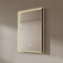 BAI 21030 modern rectangular 24-inch wall-mounted mirror with a slim warm LED light with gold frame, shown against a textured beige wall. The mirror has small control touch sensor dots near the bottom center.