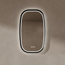 BAI 21040 modern oval LED-backlit vanity bathroom mirror with a sleek black frame, mounted on a textured beige wall with white front and side lighting.