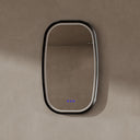 BAI 21040 modern oval LED-backlit vanity bathroom mirror with a sleek black frame, mounted on a textured beige wall with the lights off.