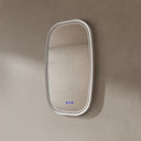 BAI 21042 modern oval LED-backlit wall bathroom mirror with a white frame and illuminated border, mounted on a textured beige plaster wall with the lights off.