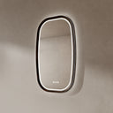 BAI 21044 modern oval LED-backlit vanity bathroom mirror with a dark wood walnut frame, mounted on a textured beige wall with white lighting side view.