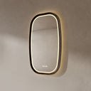 BAI 21044 modern oval LED-backlit vanity bathroom mirror with a dark wood walnut frame, mounted on a textured beige wall with warm lighting side view.