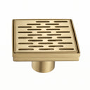 A square brushed gold shower drain cover with horizontal slotted grates and a cylindrical base, shown on a plain white background.